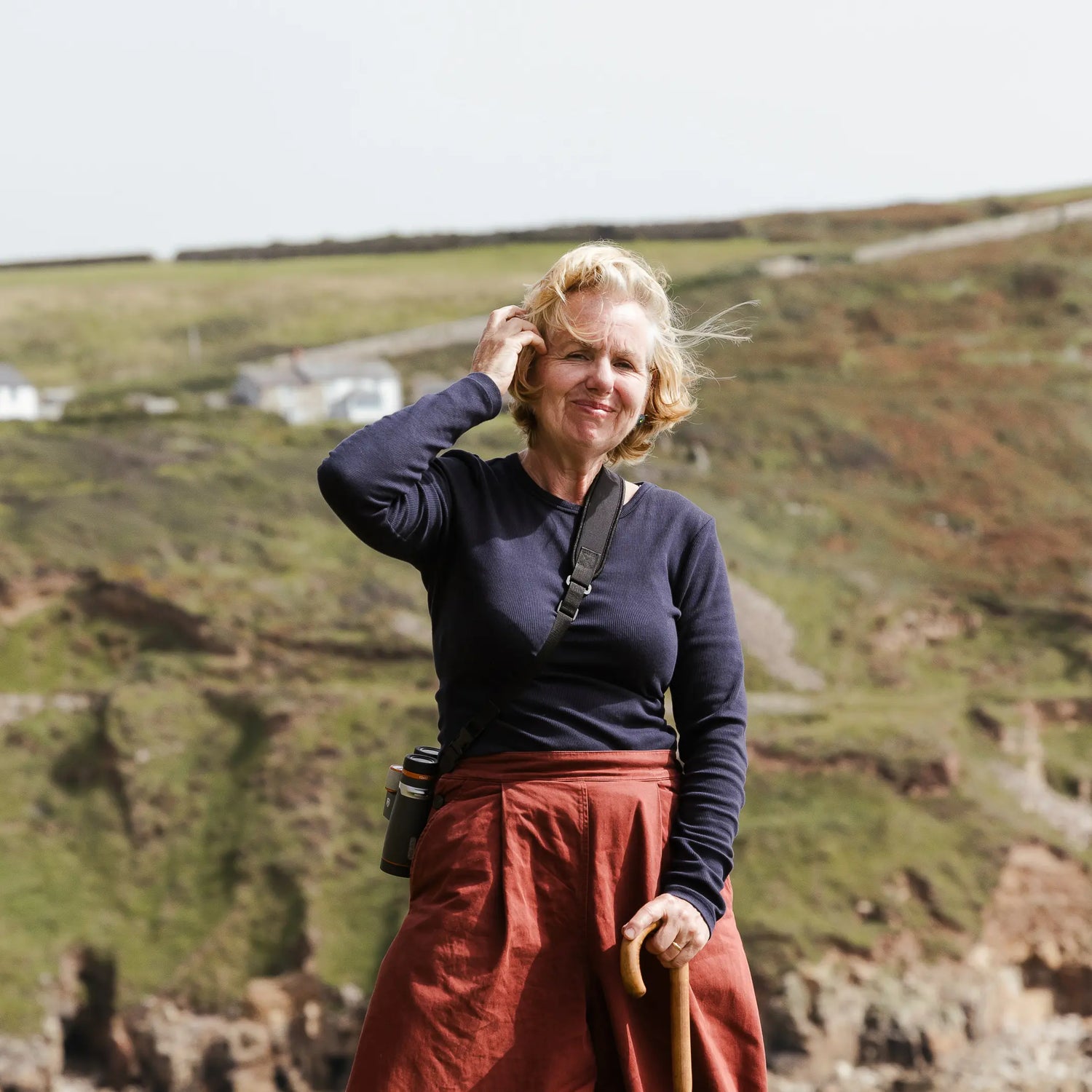 A portrait of Angela Harding against a background of cliffs and grassland