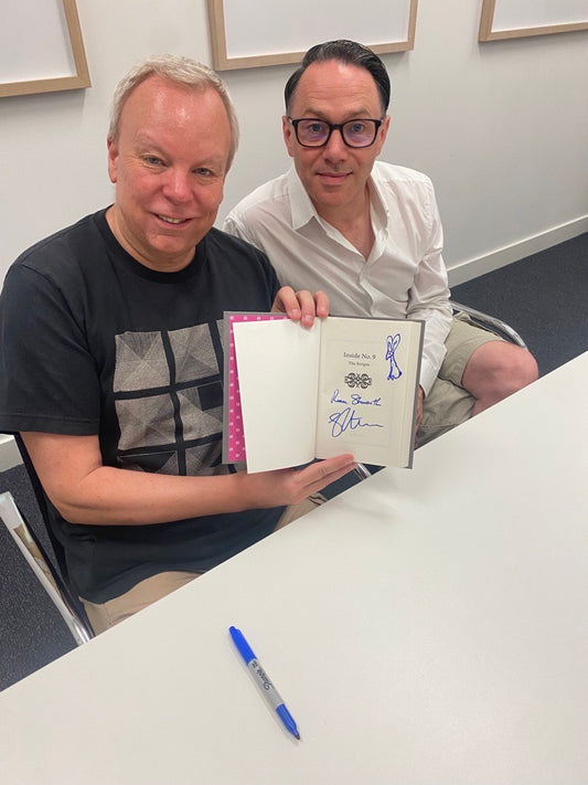 Reece Shearsmith and Steve Pemberton holding their signed book. A blue marker lies on the desk in front of them which they have used for this signed Limited Edition Book